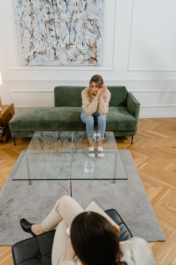 A woman in a therapy session indoors, reflecting emotions with a therapist.